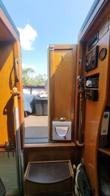 Interior view of a vintage wooden vehicle cabinet with a door open and a scenic background.